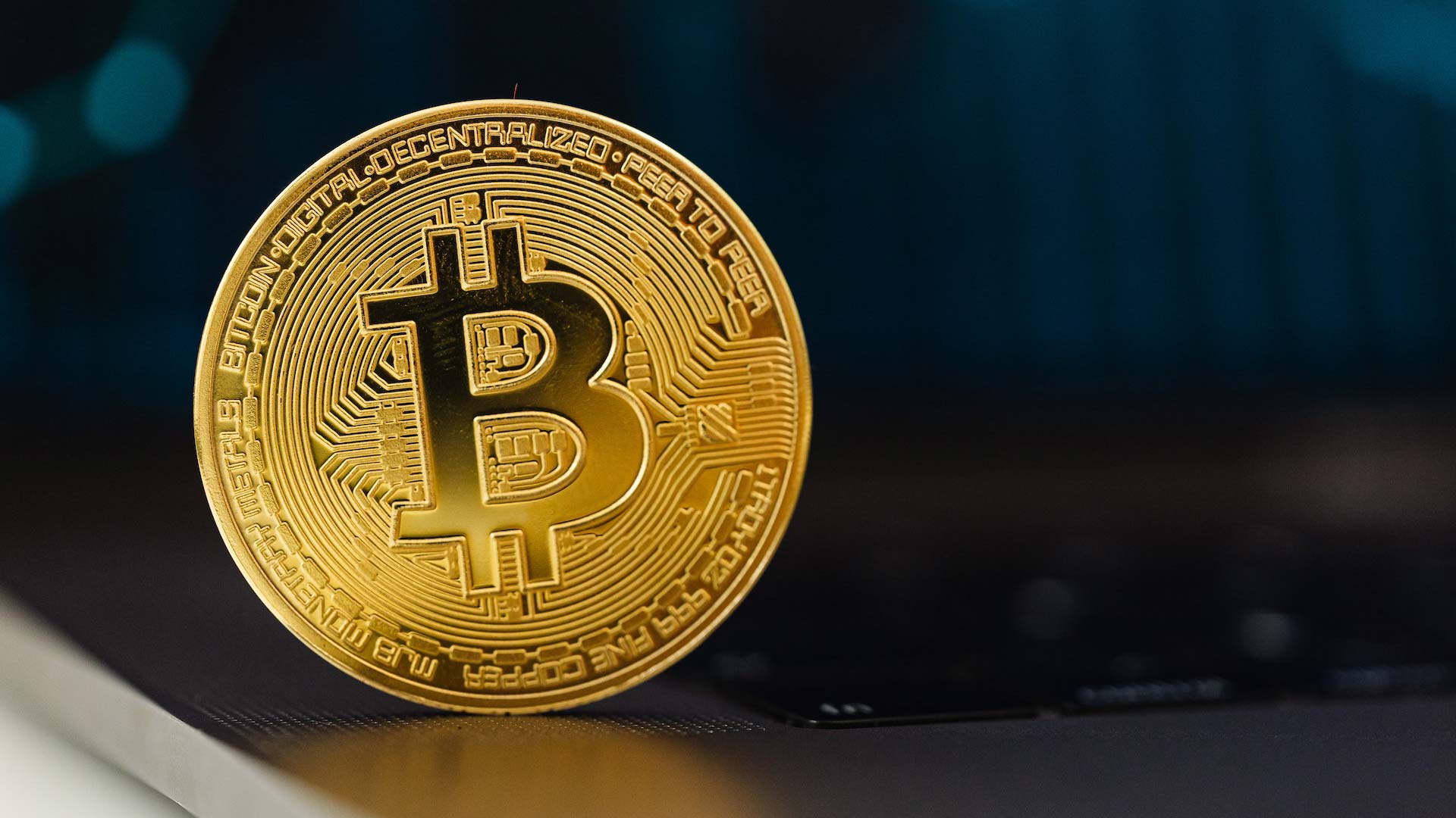 Goldene Bitcoinmünze auf einem spiegelnden Untergrund